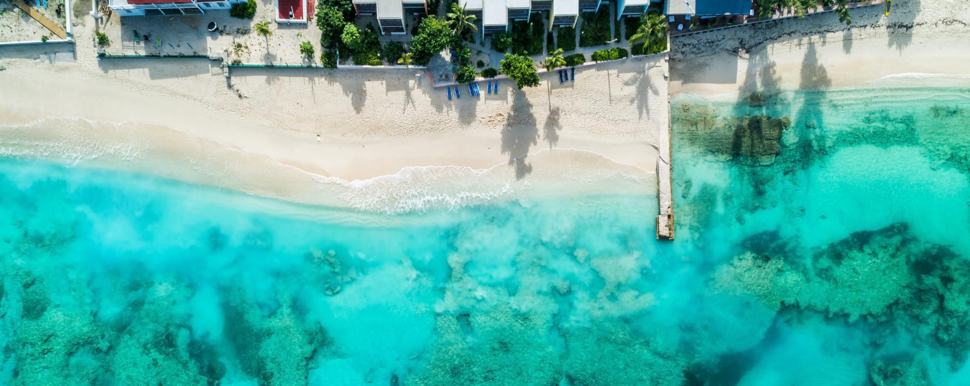 Beach with pier and coastline. Caribbean clear ocean water, coral reefs. Aerial view. Summer background